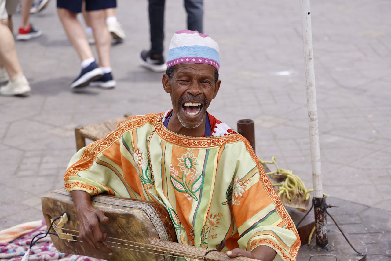 Home A vibrant portrait of a Gnawa musician singing and playing an instrument on the streets of Morocco.