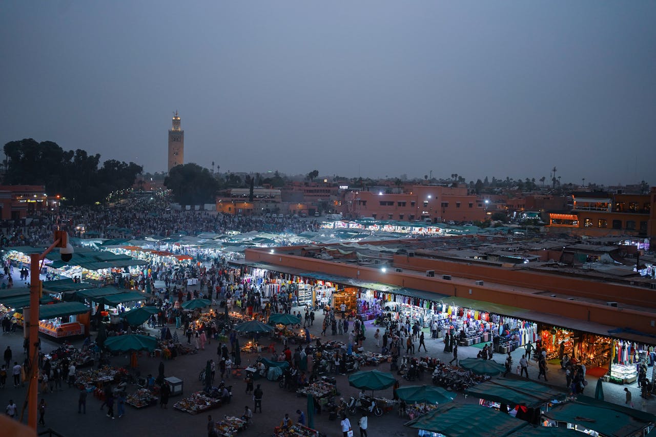 Home Aerial view of lively evening marketplace in Marrakech, filled with people and vibrant stalls.