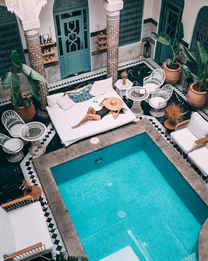 Elegant indoor pool with a woman lounging, set within a Moroccan riad in Marrakesh.