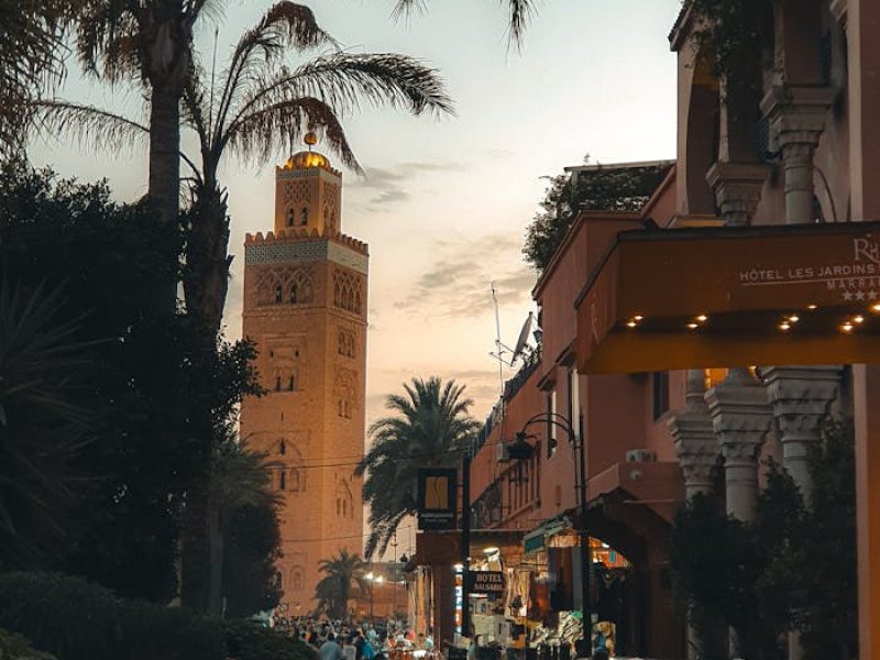 Explore the vibrant Marrakech streets at sunset, featuring iconic minaret and lively atmosphere.